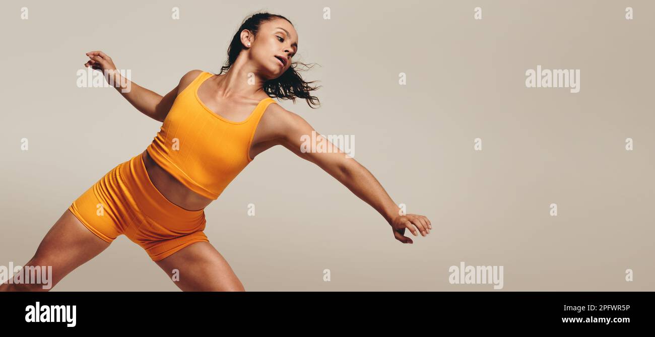 Eine aktive Frau demonstriert ihre Beweglichkeit und Balance in einem sportlichen Studio-Workout. Frau in Sportkleidung, die Muskeltoning und Fitness-Engel betreibt Stockfoto