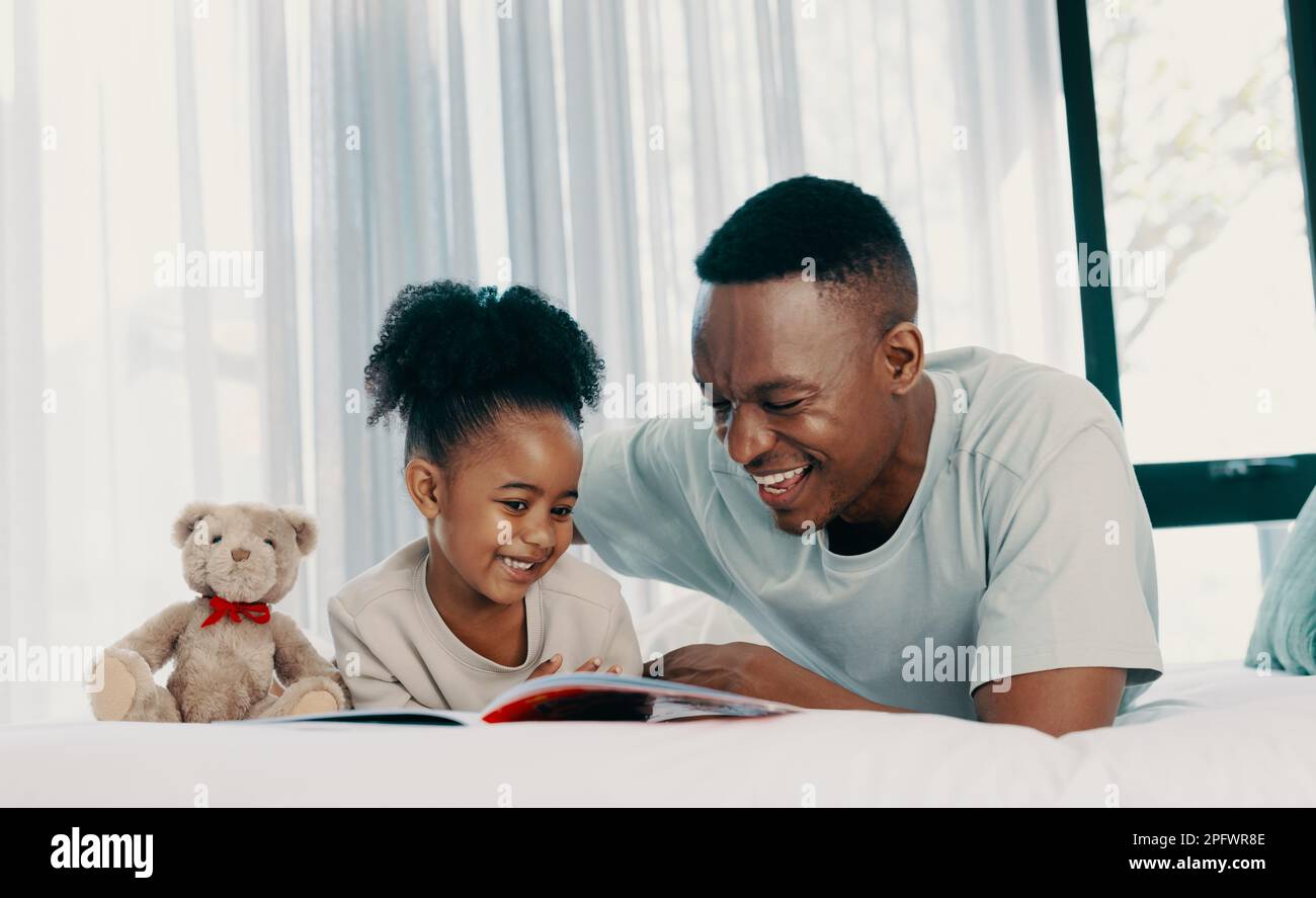Vater liest mit seiner Tochter tagsüber eine Geschichte, während er auf einem Bett liegt. Ein Mann, der sein Kind als alleinerziehender Vater erzieht. Vater und Tochter genießen das Lernen Stockfoto