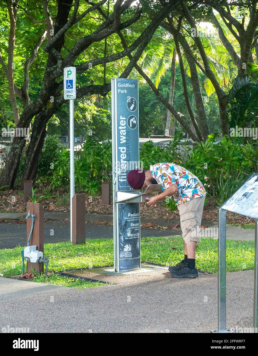 Asiatischer Mann, der aus einem öffentlichen Brunnen trinkt, Palm Cove, Cairns Northern Beaches, Far North Queensland, FNQ, QLD, Australien Stockfoto