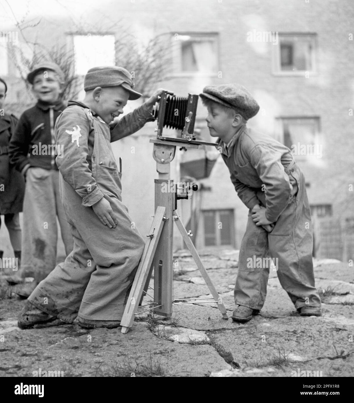 Jungs in den 1940er. Ein neugieriges Kind schaut mit seinem Freund in eine Kamera, die auf einem Stativ befestigt ist. Schweden 1945. Kristoffersson Ref. N107-6 Stockfoto