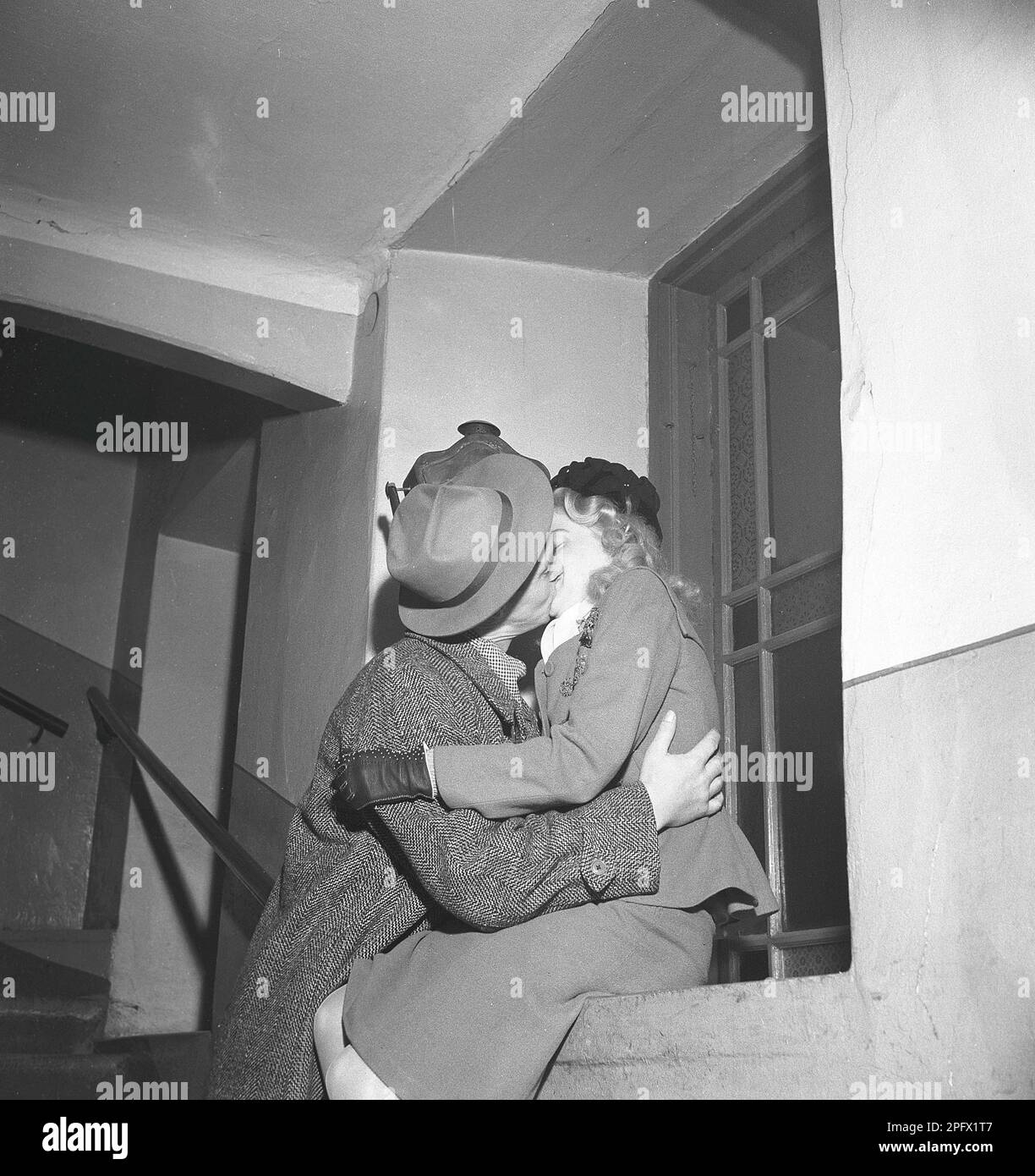 Küssen im 1940er. Jahrhundert. Ein junges Paar sah Küsse und Umarmungen auf der Treppe eines Wohngebäudes. Vielleicht einen gute-Nacht-Kuss. Schweden 1946 Kristoffersson Ref Y7-1 Stockfoto