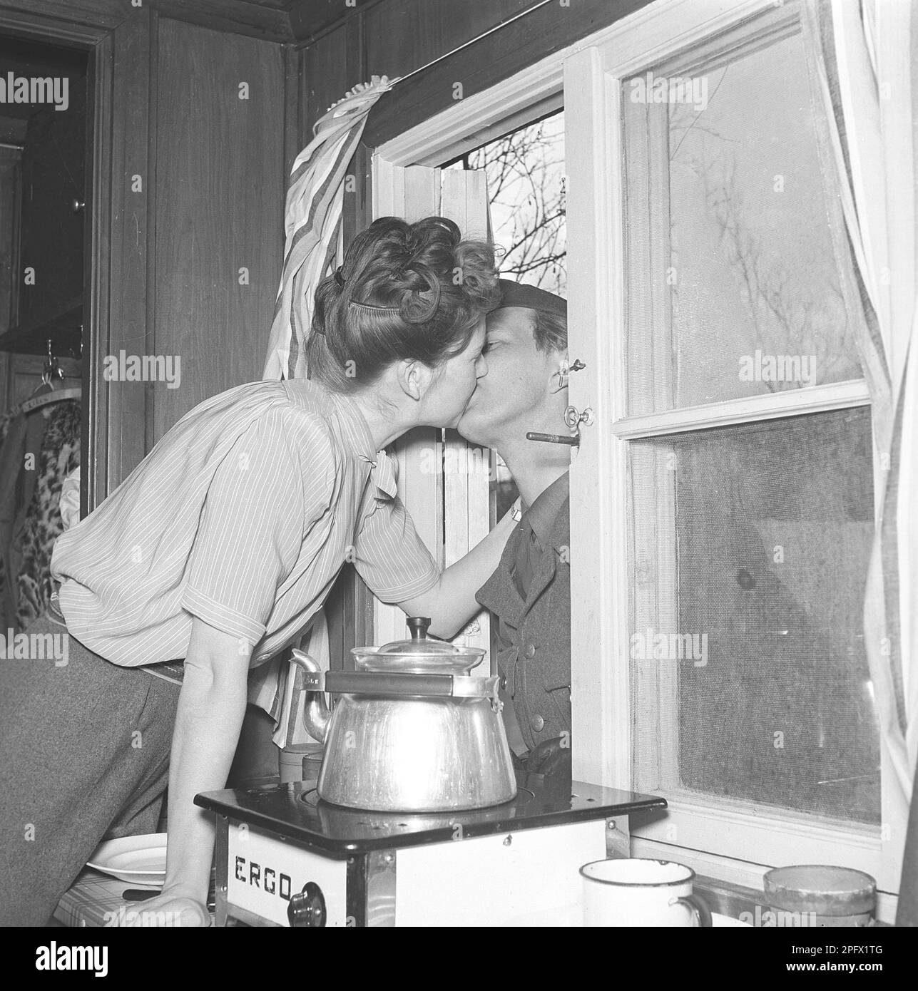 Küssen im 1940er. Jahrhundert. Frisch verheiratete Iris mit Ehemann Bertil küsst sich durch das offene Fenster. Zu dieser Zeit im Zweiten Weltkrieg von 1940er ist er im Militärdienst und seine Station befindet sich in den Bergen des schwedischen Lapplands in der Nähe von Abisko. Schweden 1943 Kristoffersson Ref D110-1 Stockfoto