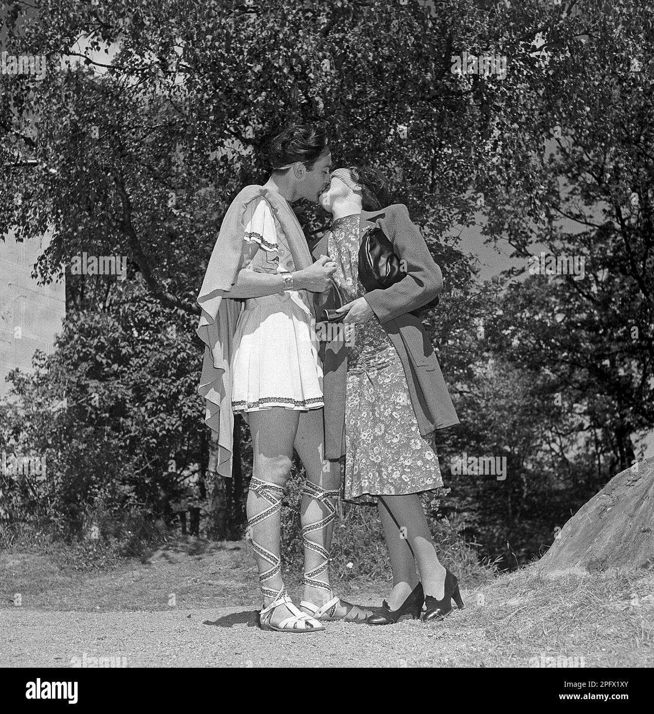 Historische Romantik. Ein junges Paar, das sich küsst. Er trug sein römisches Theaterkostüm und sie trug ihre typischen 1940er Kleider, ein Kleid und einen Mantel. Vielleicht ein Glückskuss, bevor er auf die Bühne geht. Wer weiß. Schweden 1946 Kristoffersson Ref U106-4 Stockfoto