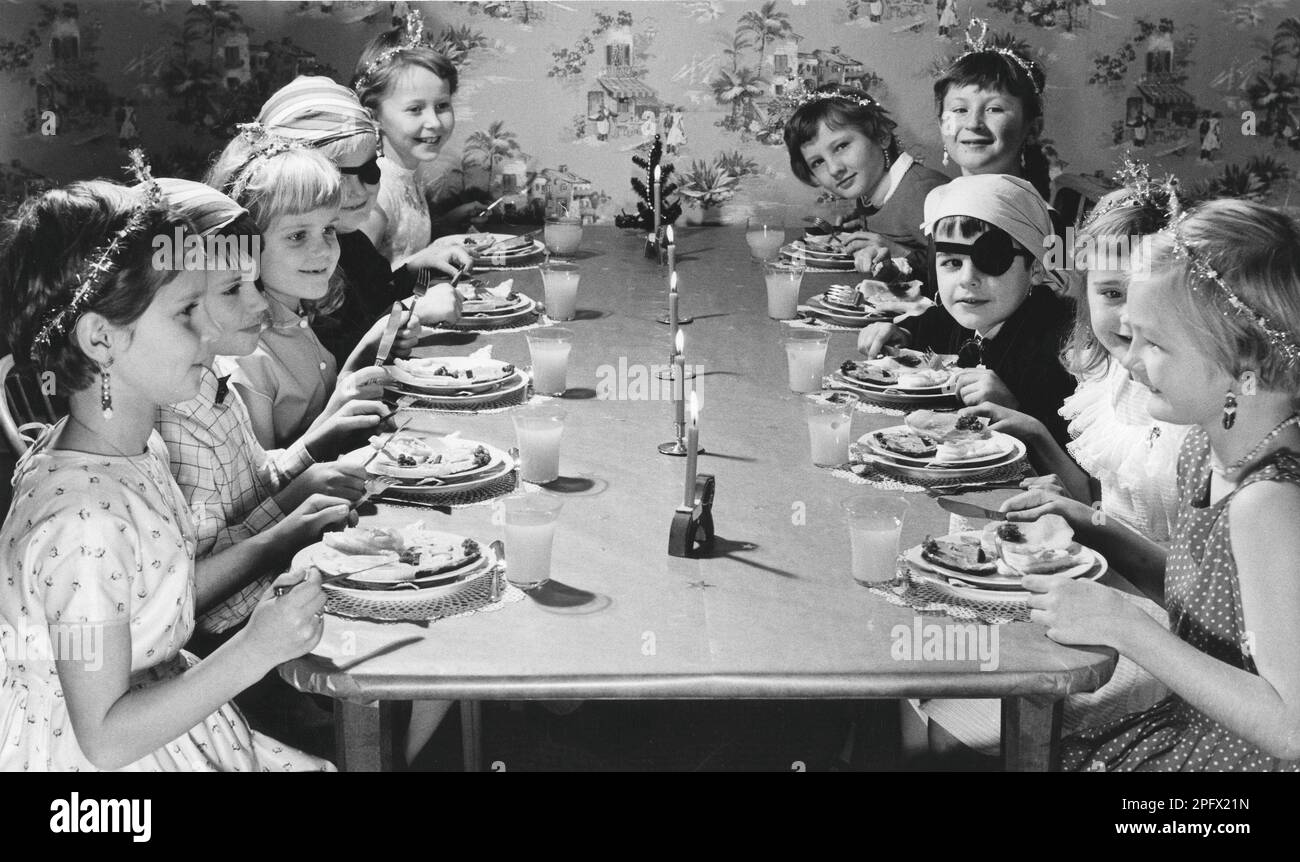Kinder im 1950er. Jahrhundert. Mädchen und Jungen in Hüten und Kostümen sitzen zusammen an einem Tisch, feiern etwas, essen Kuchen und essen Limonade. Schweden 1957 Stockfoto