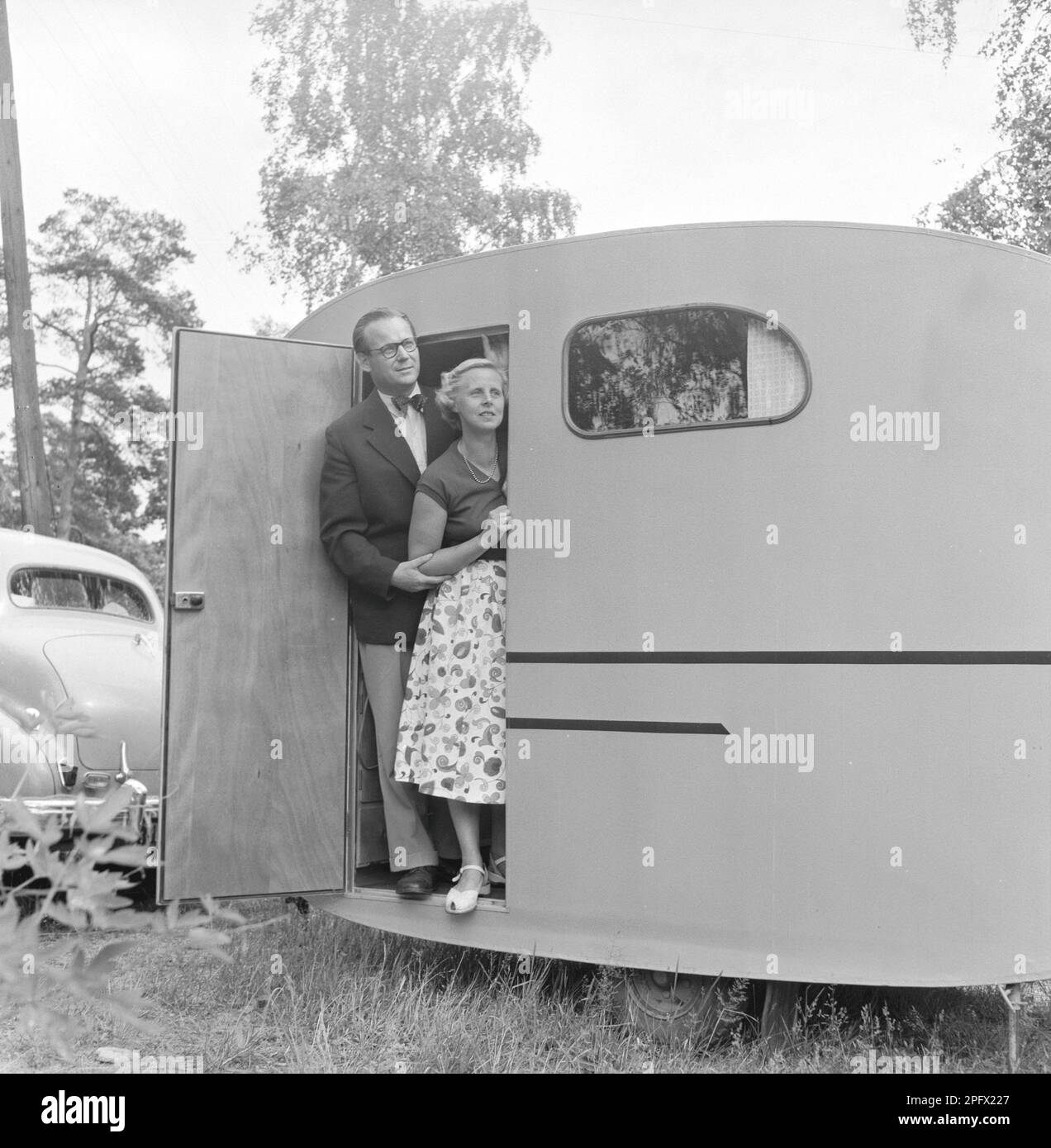 Wohnwagen mit Besitzer Sten Hesser und Frau, die vor der Tür stehen. Das Bild veranschaulicht die Zeit in den 1950er Jahren, als Menschen in größerer Zahl ein Auto hatten und damit Gelegenheiten hatten, im Juli in Schweden zu reisen und Urlaub zu machen. 1953. ref. SSMSAX000433L Stockfoto