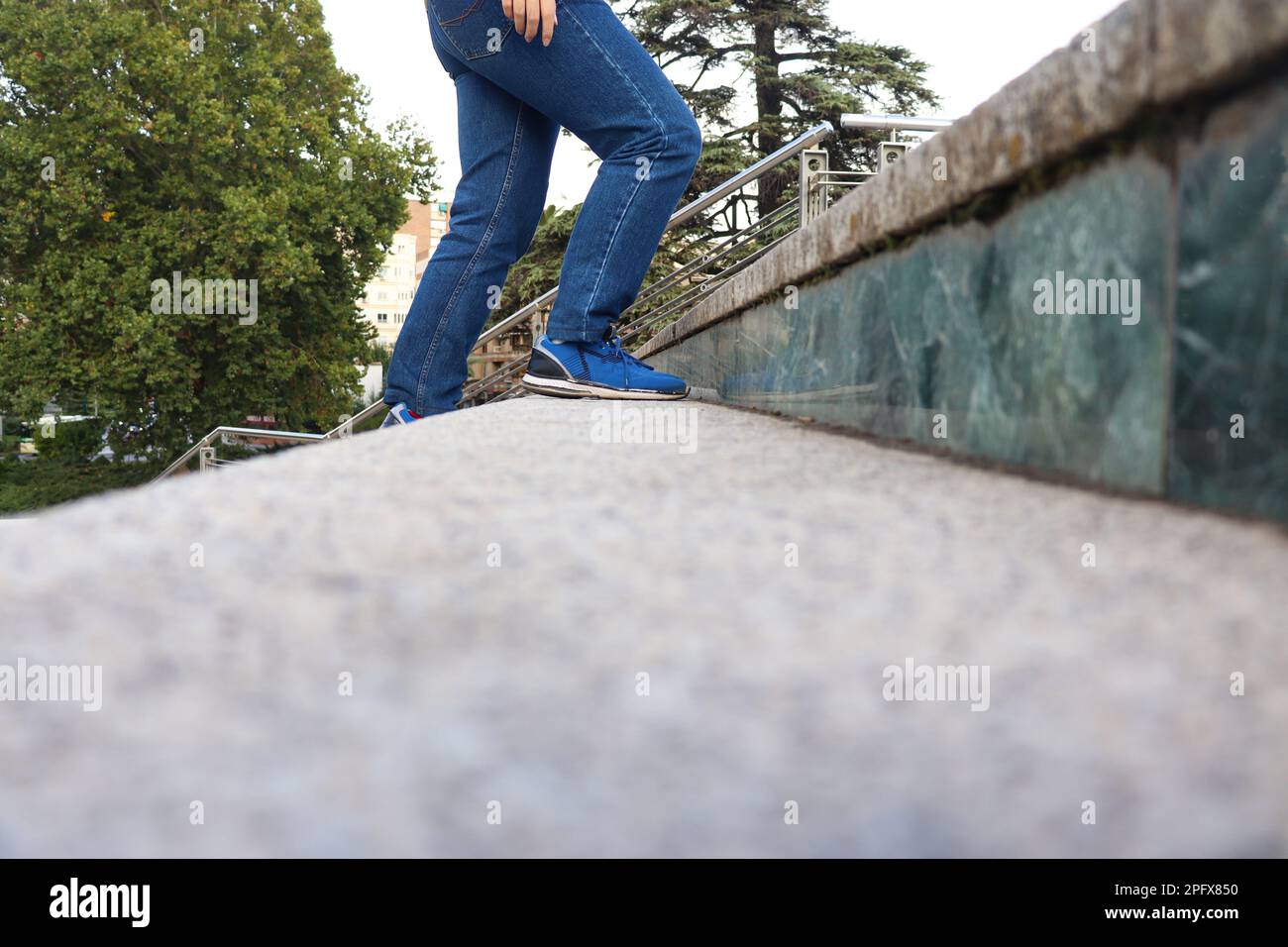 Eine Person mit blauen Jeans und Schuhen, die die Treppe hinaufgeht Stockfoto