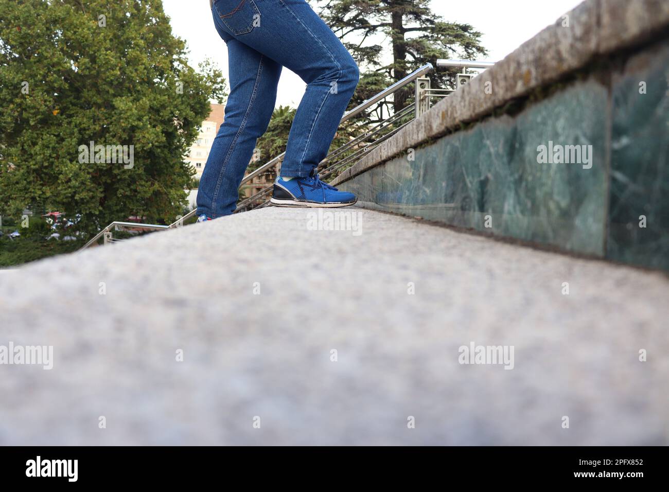 Eine Person mit blauen Jeans und Schuhen, die die Treppe hinaufgeht Stockfoto