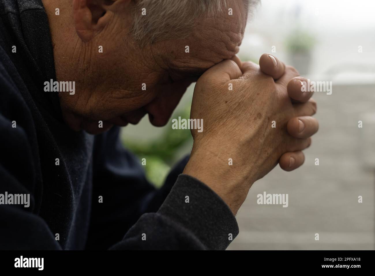 Besorgter religiöser Seniorist betet mit erhobenen Händen zu gott und rührt sich, während er um Hilfe und Inspiration betörend in den Himmel schaut. Stockfoto