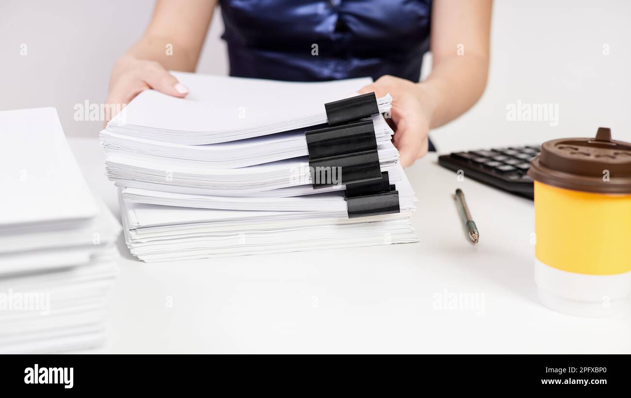 Ein Büroangestellter transportiert einen Stapel Papier, das mit Heftklammern befestigt ist Stockfoto