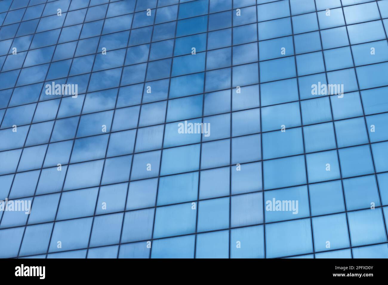 Bruchteil eines großen Gebäudes mit einer Glasfassade. Abstrakter architektonischer Hintergrund. Reflexion des Himmels in Fenstern Stockfoto