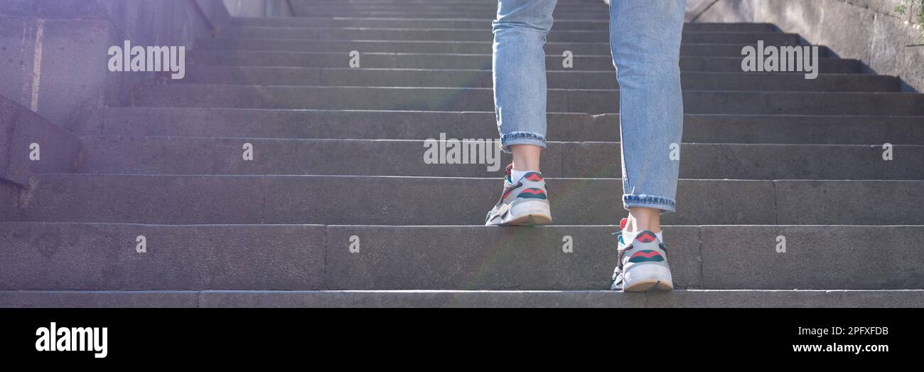 Frau in Jeans, die eine steile Treppe hinaufsteigt Stockfoto