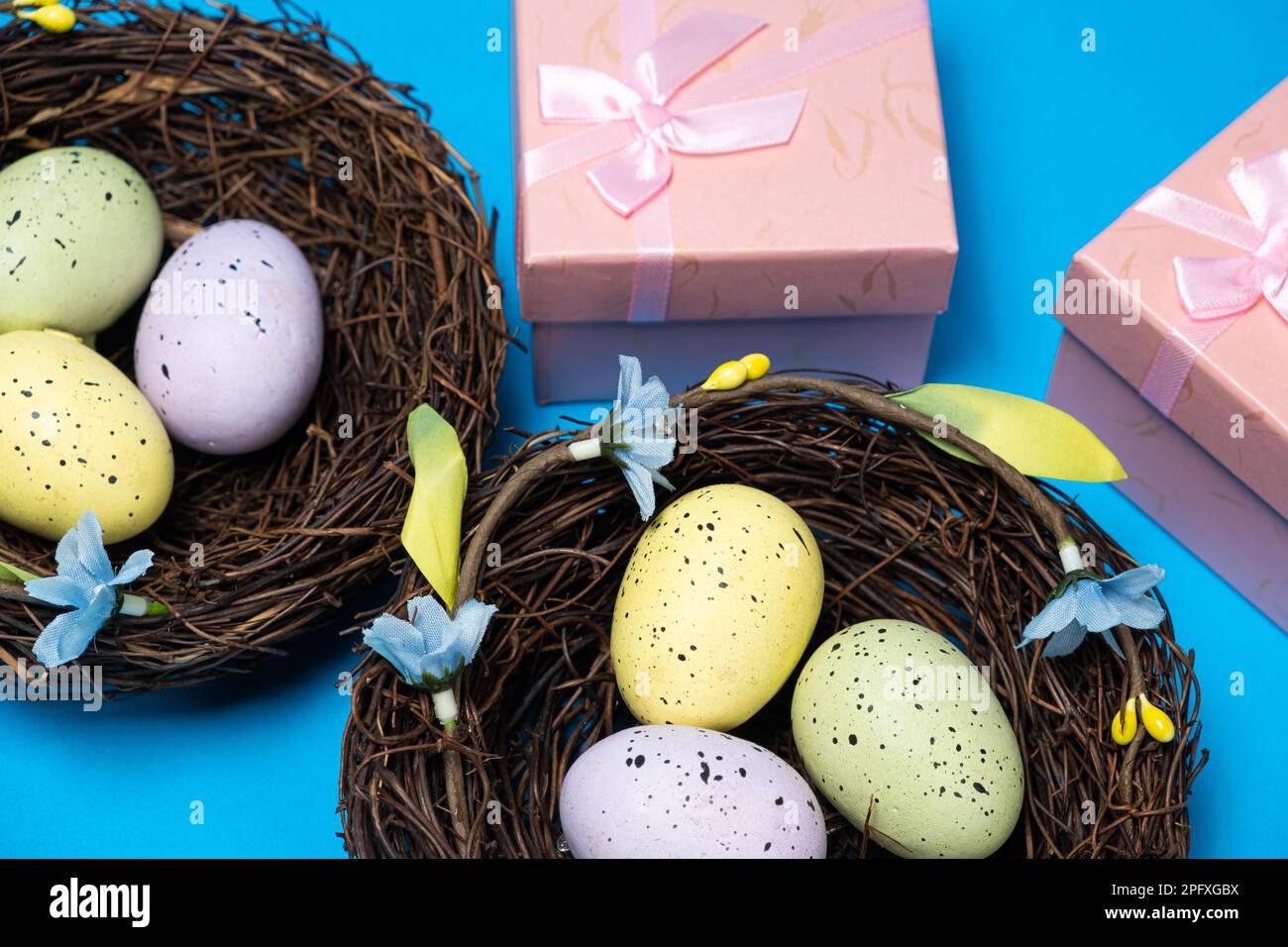 Geschenke zu Ostern, Osterverkauf. Eier in Nestern und Geschenkschachteln auf blauem Hintergrund. Stockfoto