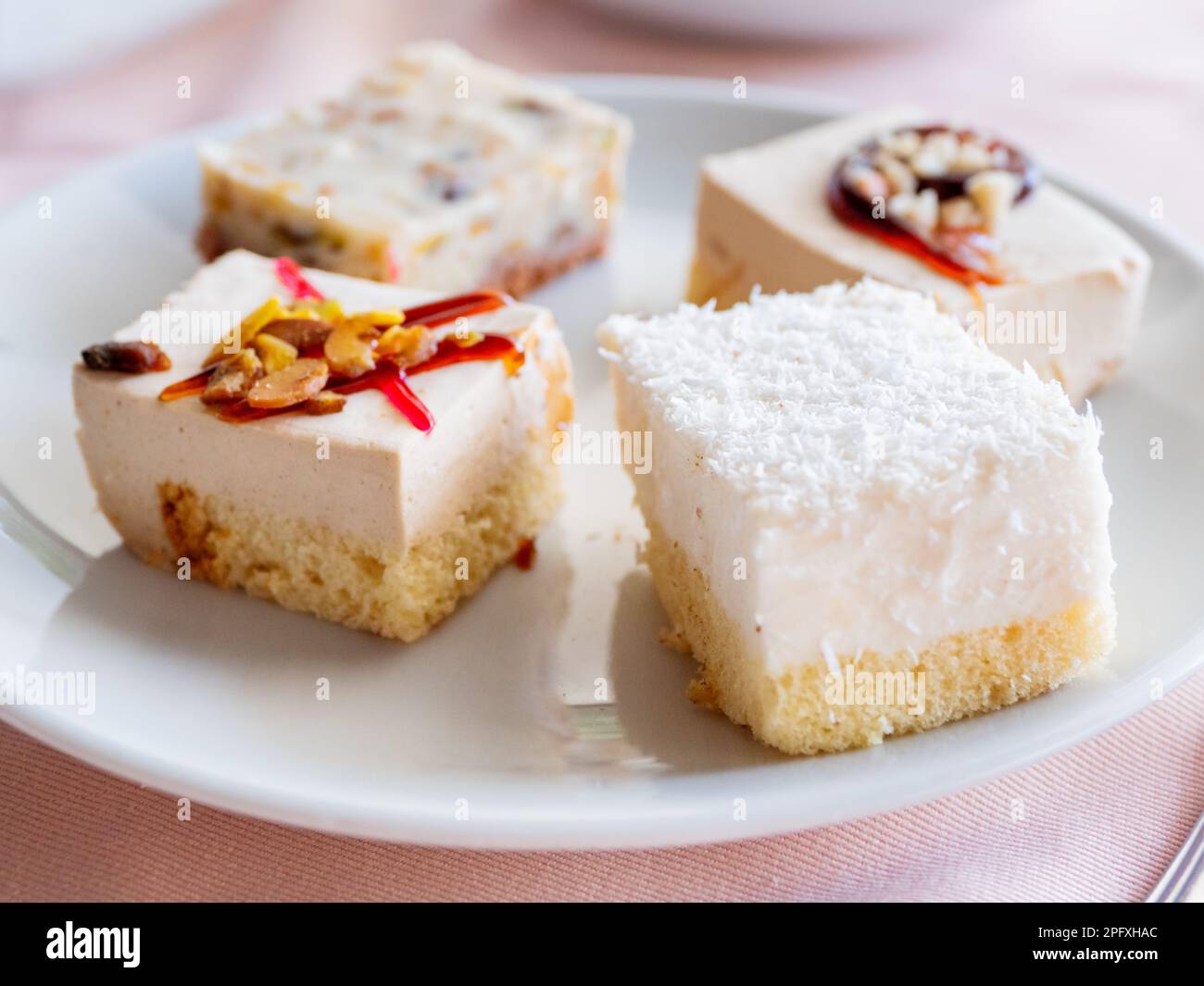 Weißer Teller mit verschiedenen Gebäckstücken. Leckere Desserts mit Belag, Kokosnussflocken. Stockfoto