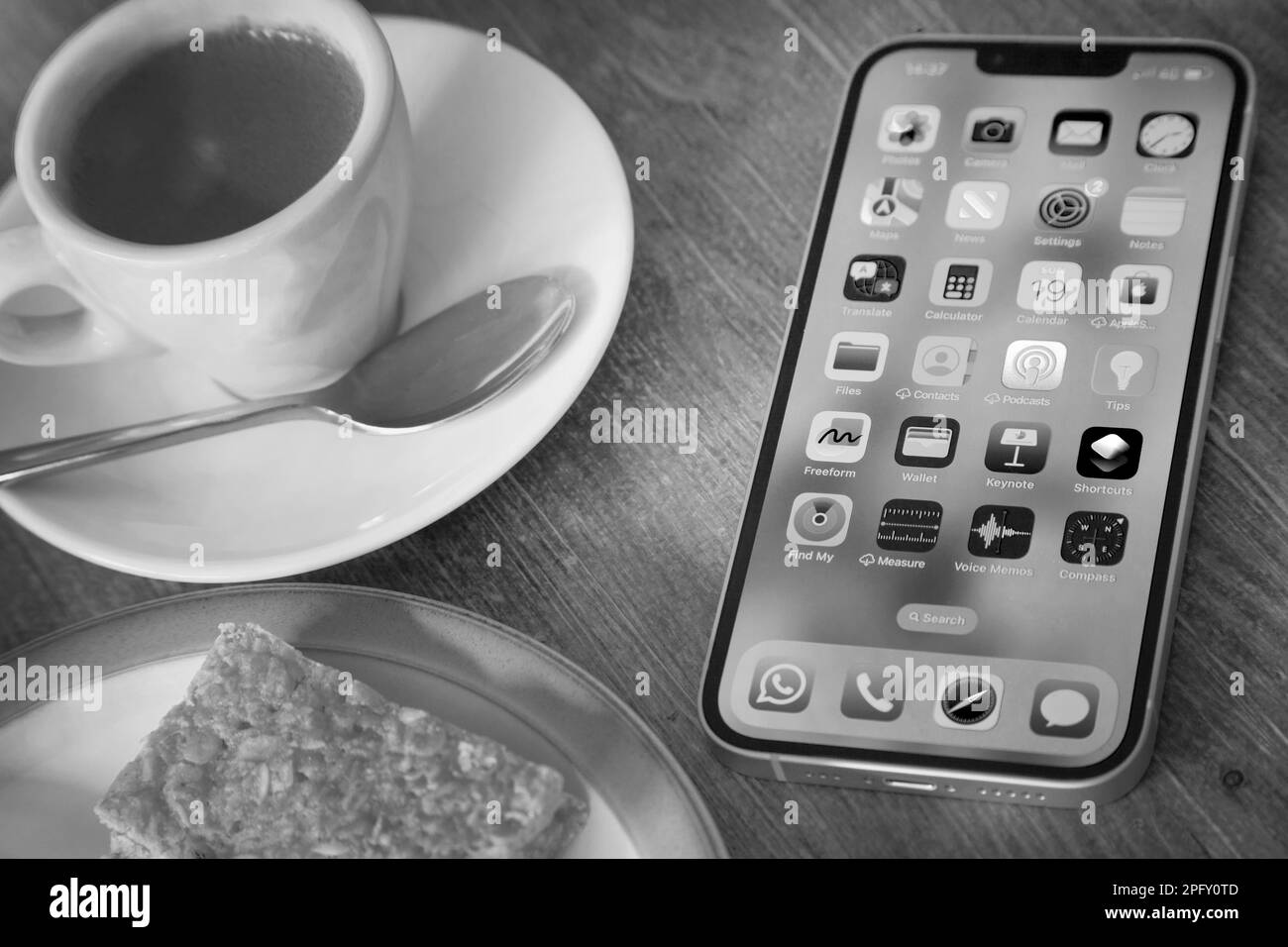 Das neueste iPhone 14 in Gelb mit Kuchen und Kaffee Stockfoto