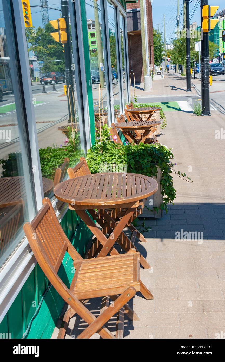 An einem sonnigen Sommertag stellten die Gastgeber Tische auf den Gehweg in der Nähe des Cafés Stockfoto