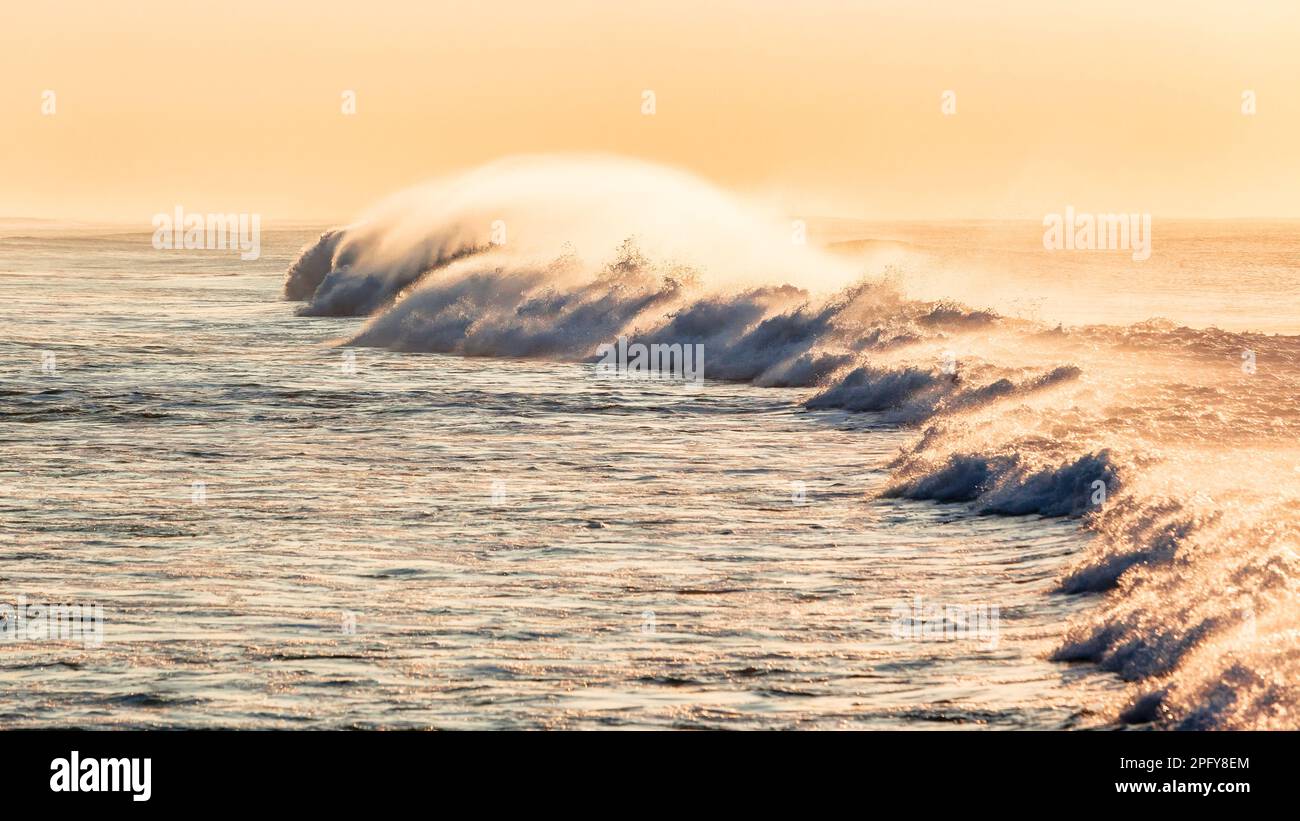 Meereswelle stürzt ab, weißes Wasser, Wassersprühnebel rollt in Richtung Strand, Küste, Seitenansicht Foto. Stockfoto
