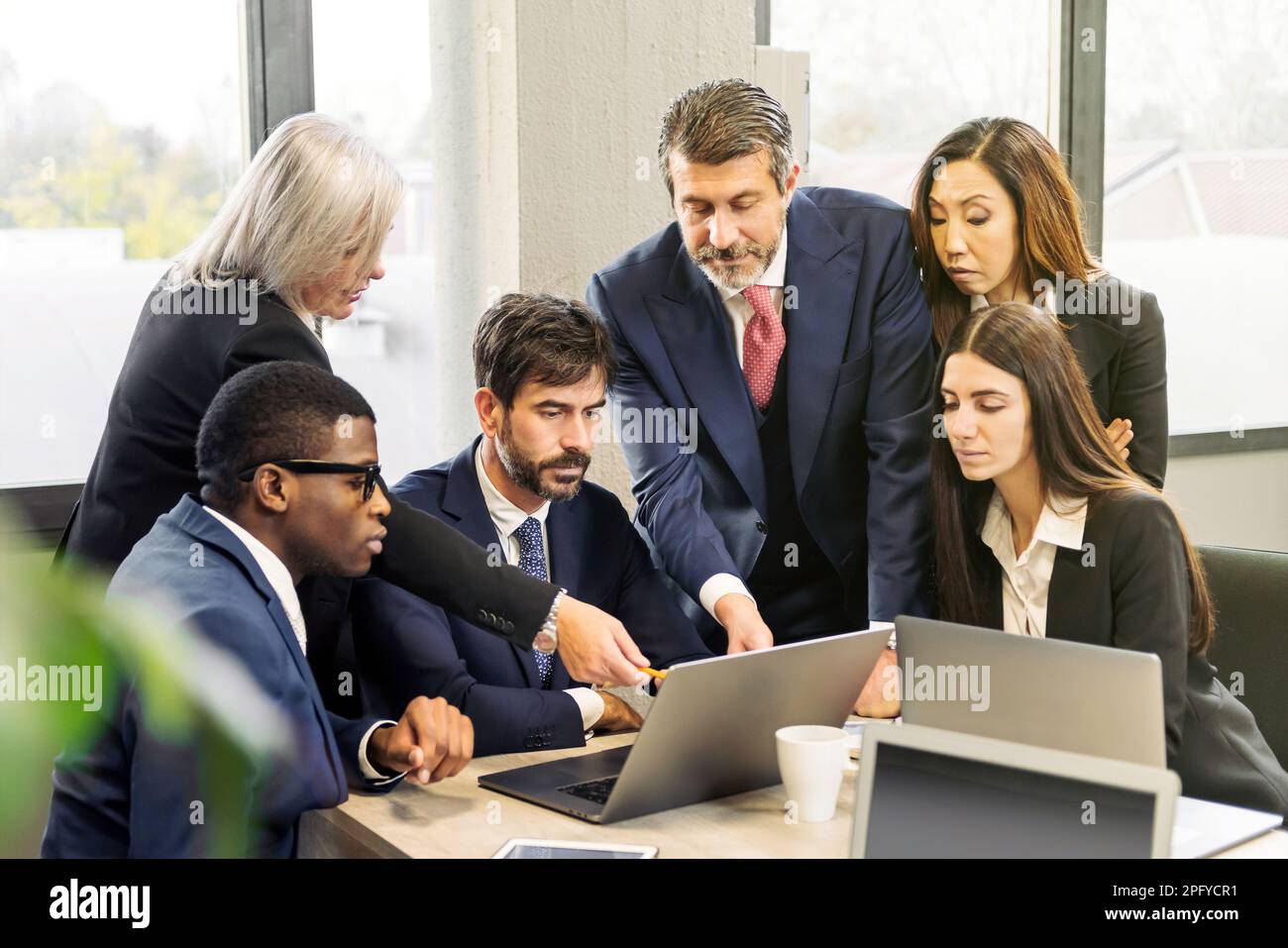 Gruppe von Geschäftsleuten aus verschiedenen Ländern, die auf den Laptop-Bildschirm zeigen und während der Arbeit im Büro über Daten diskutieren Stockfoto