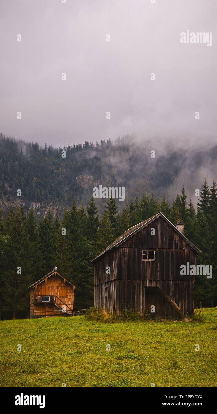 Ein vertikales Bild eines traditionellen ländlichen Hauses vor dem Hintergrund von majestätischen Bergen und üppigen Wäldern Stockfoto