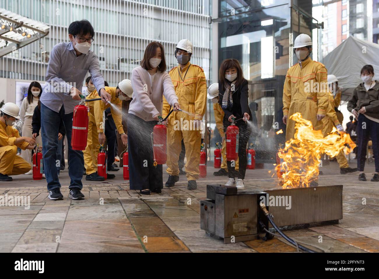 Die Teilnehmer sahen während der Katastrophenübung in Roppongi Hills unter Aufsicht der erste-Hilfe-Diffusoren des Mori-Gebäudes eine Feuersimulation. Japanische Mitarbeiter der Mori Building Company nehmen an einer Katastrophenübung in Roppongi Hills in Tokio Teil, um sich mit dem Löschen von Feuer, der ersten Hilfe und der Rauchentwicklung vertraut zu machen. Stockfoto