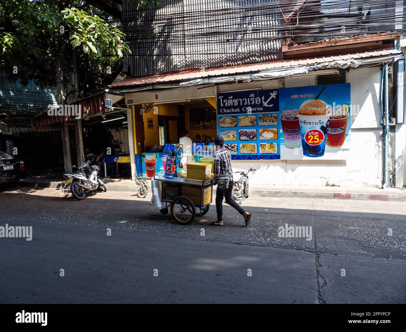 Eine Frau kocht pikante Reisbällchen auf den Straßen von Bangkok, Thailand. Sie trägt eine Gesichtsmaske, während sie traditionelle Kochutensilien verwendet. Der Reisbär Stockfoto