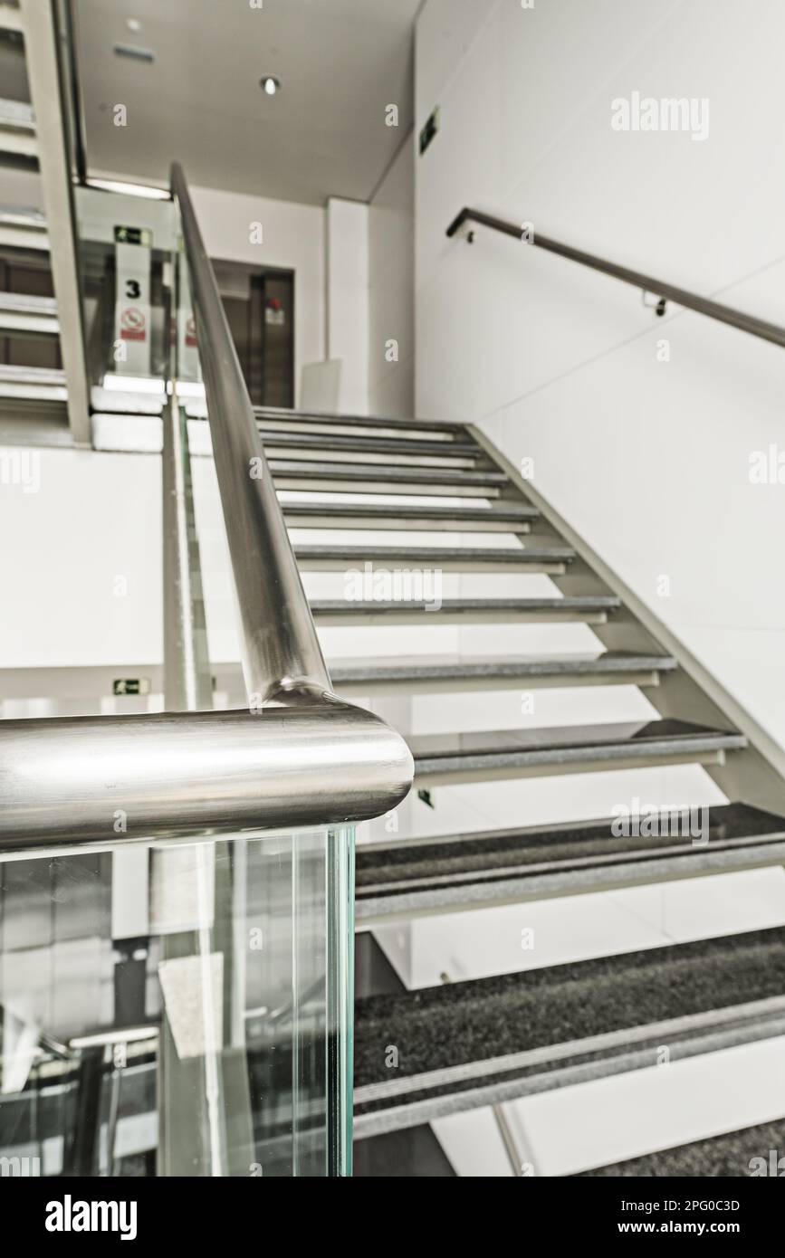 Edelstahltreppen, gehärtetes Glas und Stufen aus poliertem schwarzem Granit in einem Bürogebäude Stockfoto