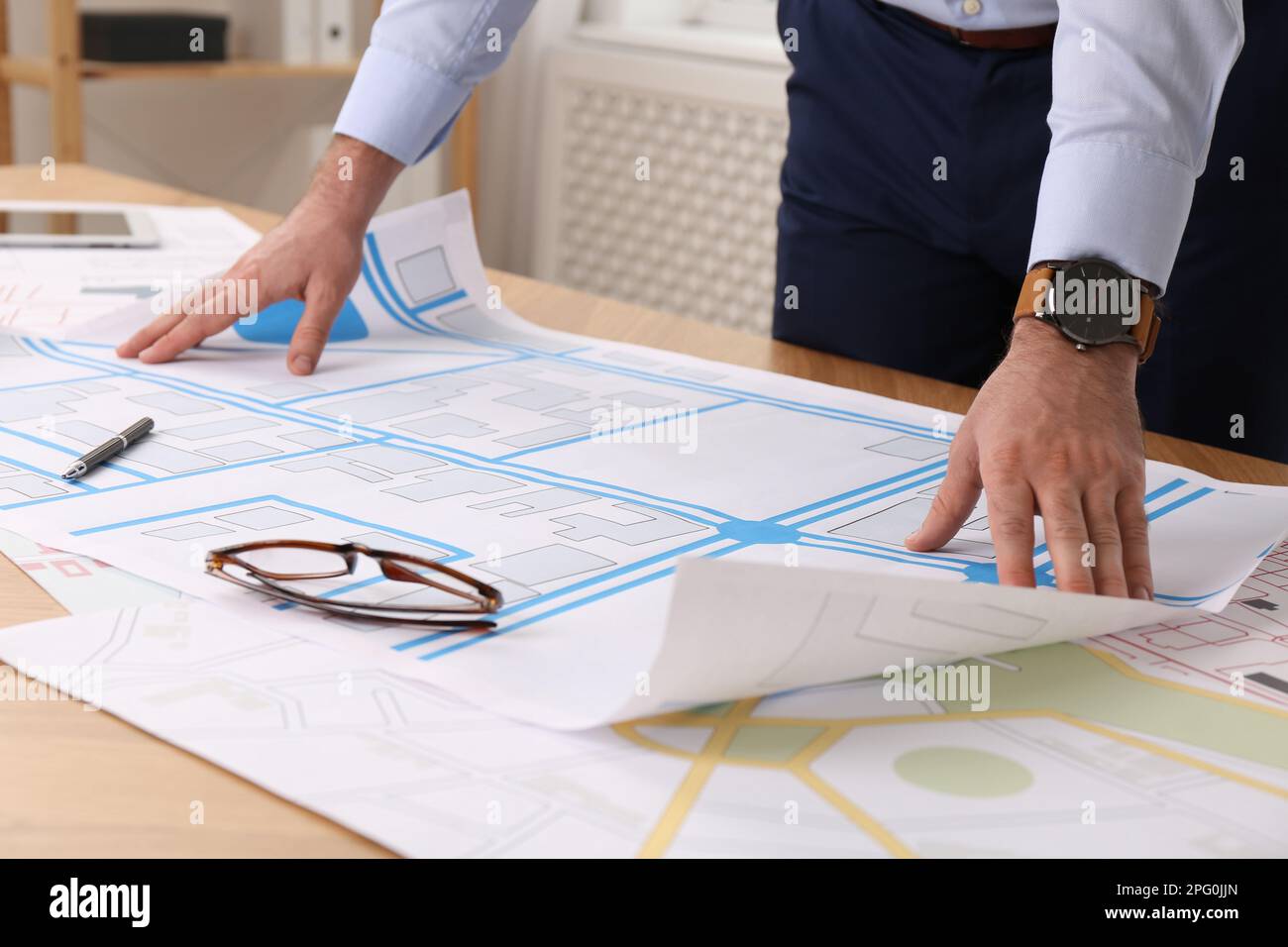 Professioneller Kartograf, der mit einer Katasterkarte arbeitet, am Tisch im Büro, Nahaufnahme Stockfoto