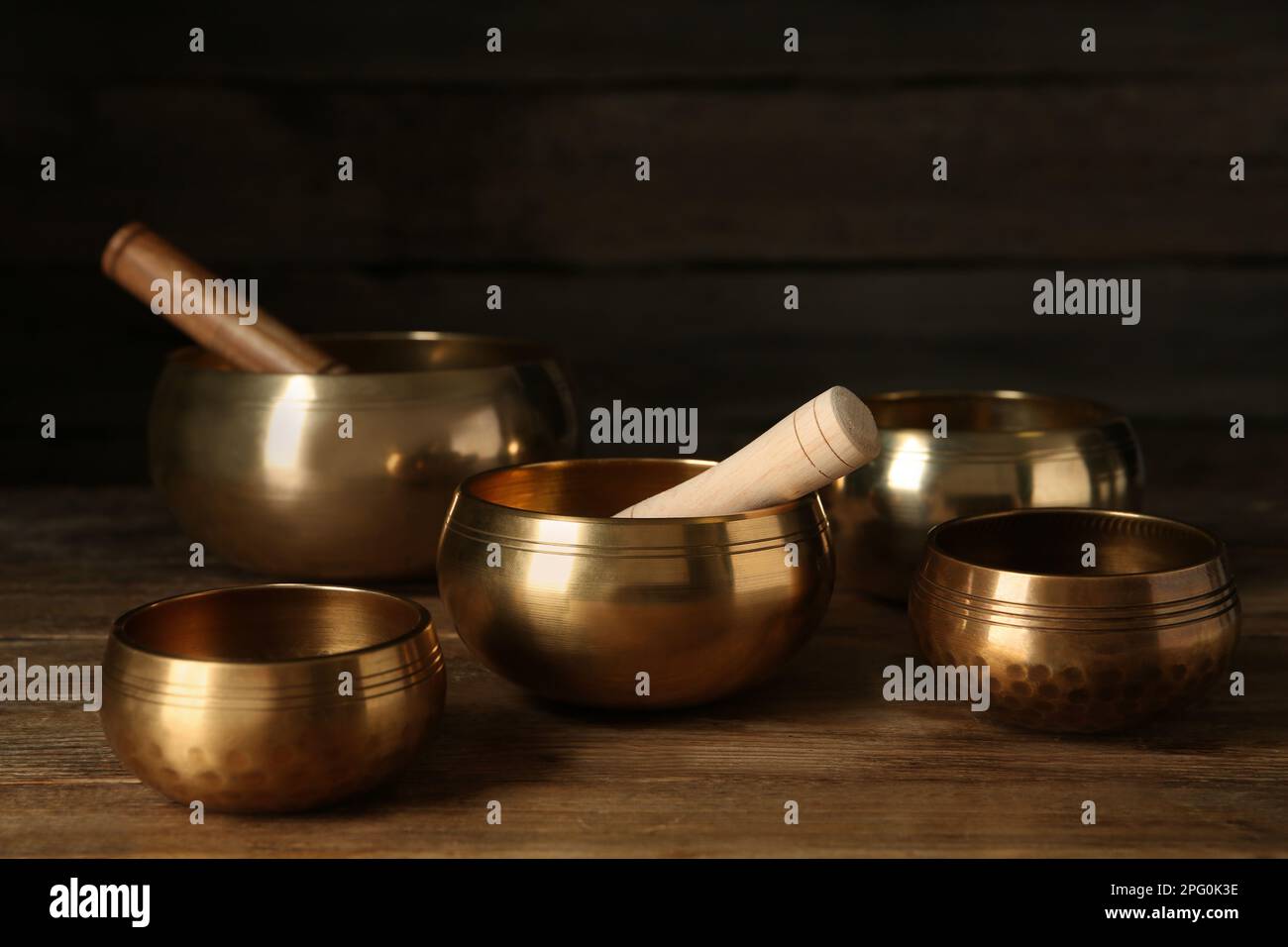 Goldene Gesangsschüsseln mit Hölzern auf einem Holztisch Stockfoto