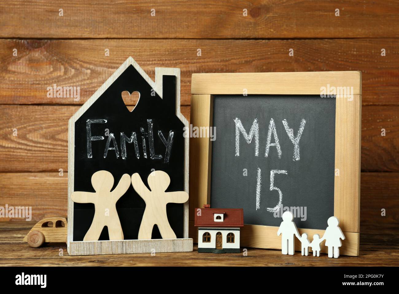 Kreidetafeln, Familienfiguren und Spielzeug auf Holzhintergrund Stockfoto