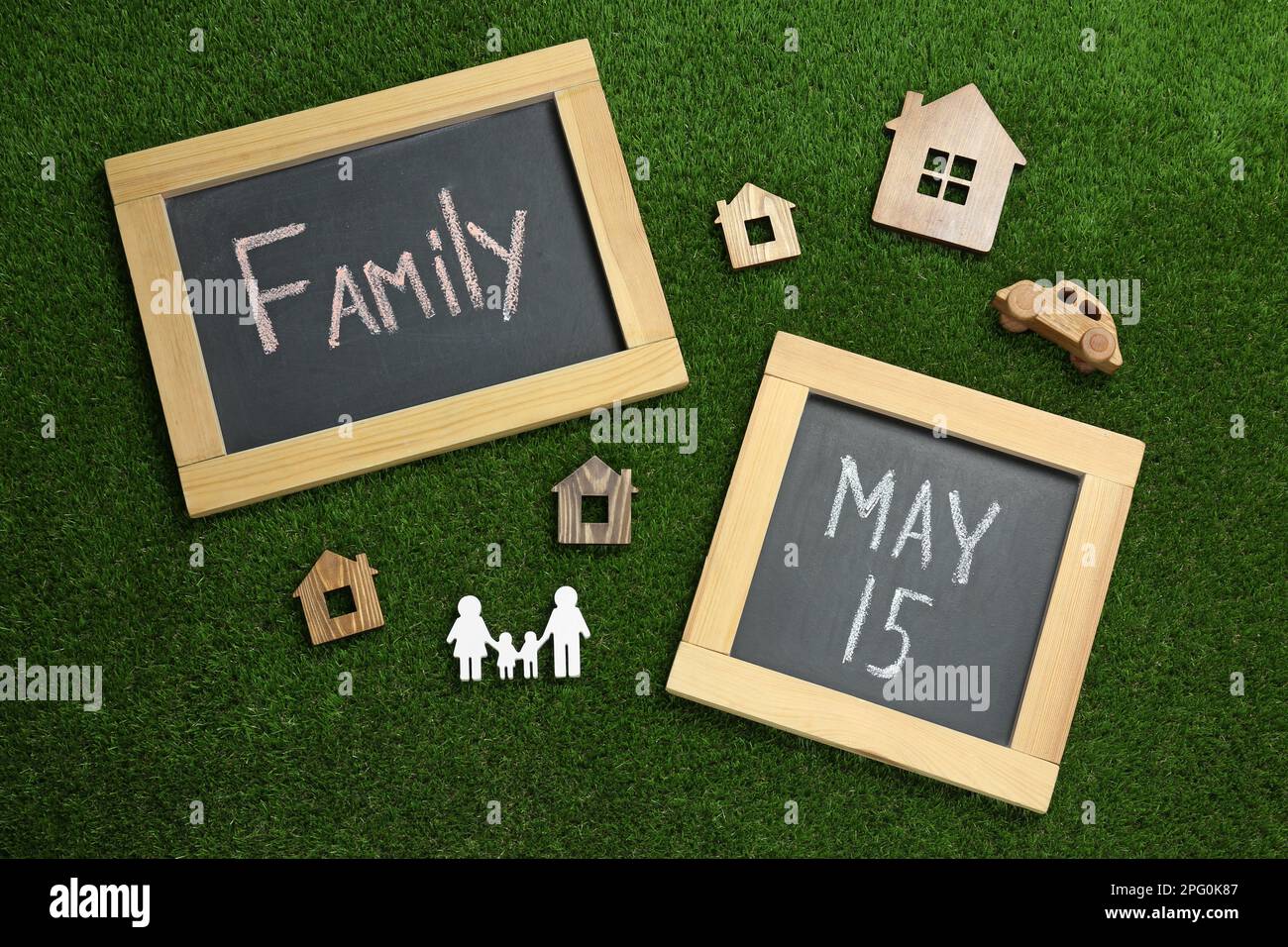 Kreidetafeln und Holzfiguren auf grünem Gras, flach liegend. Internationaler Familientag Stockfoto