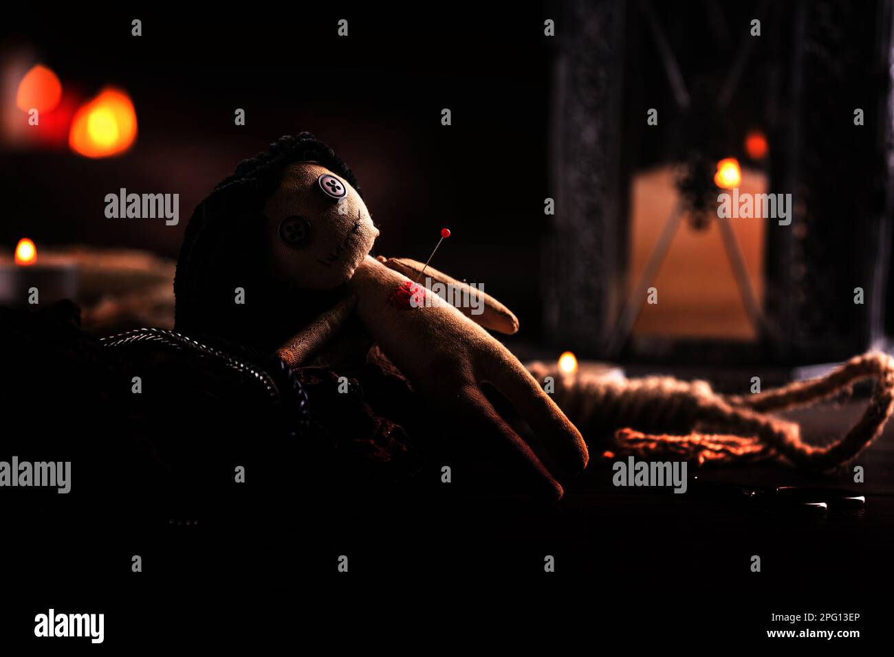 Weibliche Voodoo-Puppe mit Herznadel und zeremoniellen Gegenständen auf dem Tisch Stockfoto