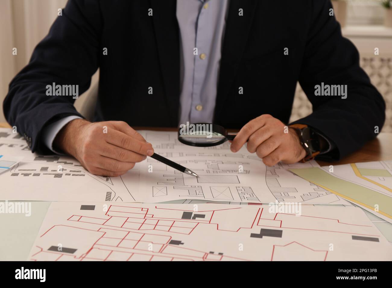 Professioneller Kartograf, der mit einer Katasterkarte arbeitet, am Tisch im Büro, Nahaufnahme Stockfoto