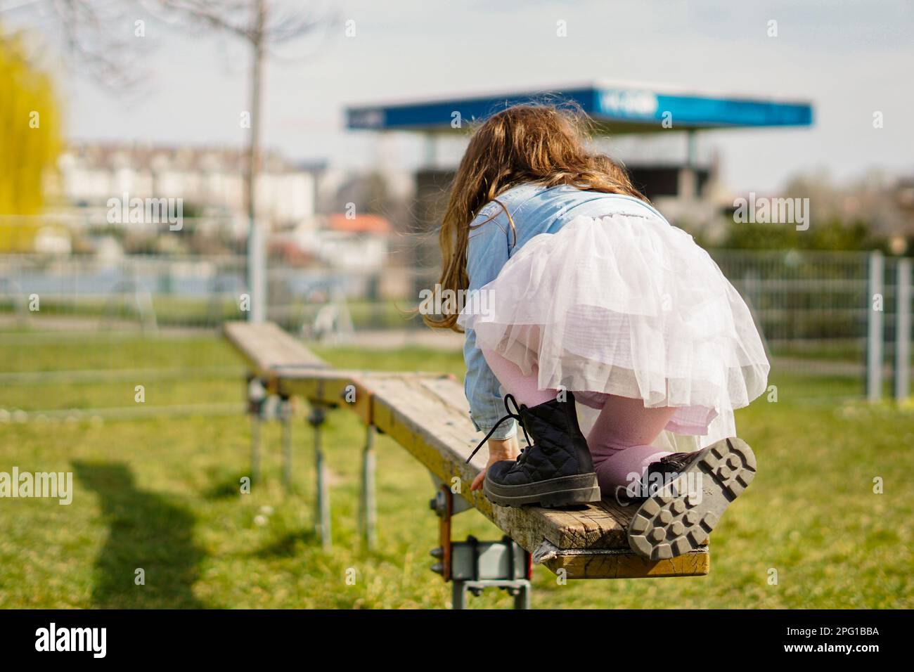 Kleines Mädchen hält das Gleichgewicht auf dem Spielplatz und macht lustige Aktivitäten - Kind spielt im Frühling draußen Stockfoto