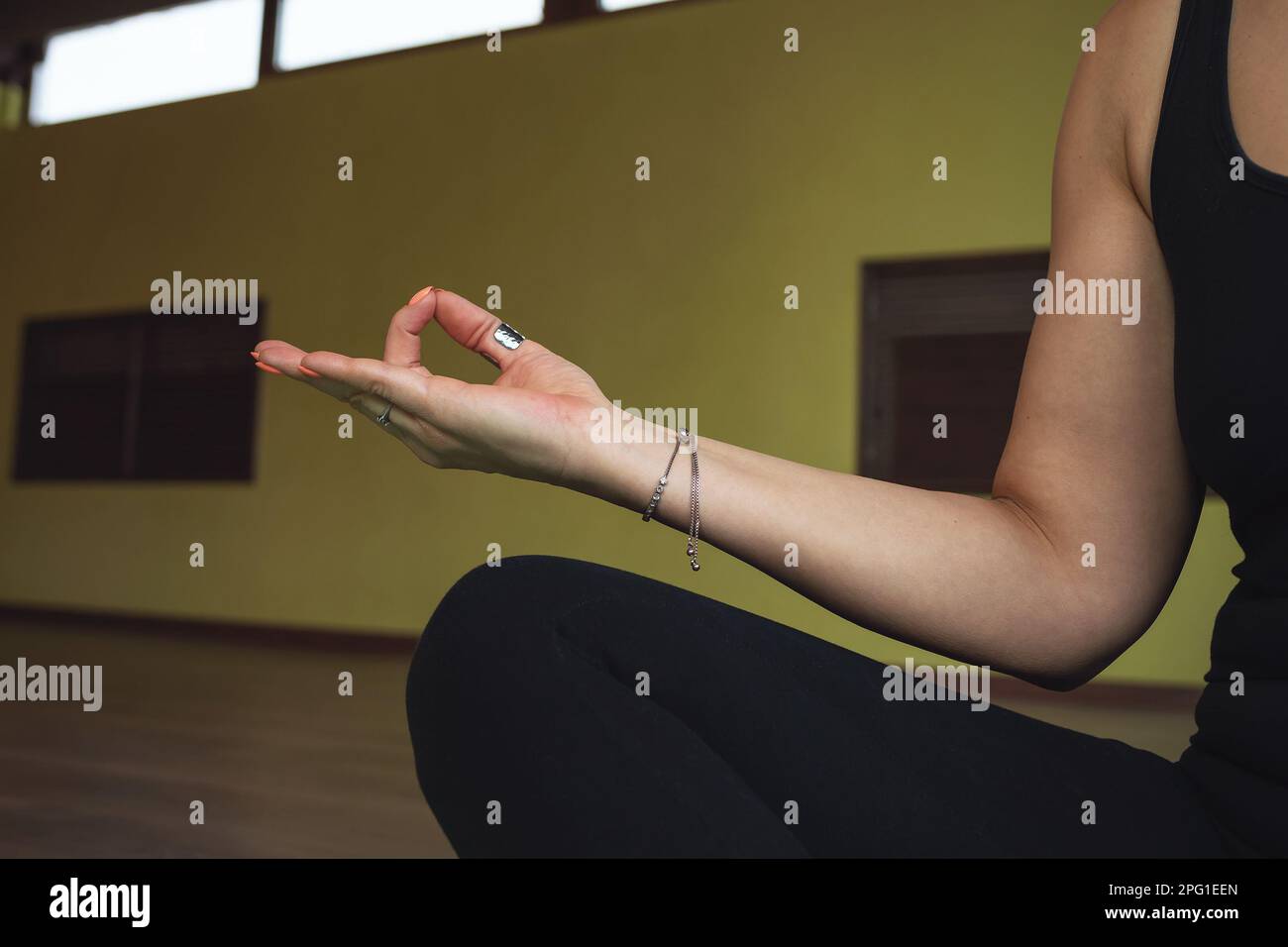 Eine meditierende Frau, die in Lotusposition sitzt, zeigt ein Symbol für Jnana mudra oder Weisheit des Wissens, trainiert in schwarzer Sportbekleidung im Studio Stockfoto