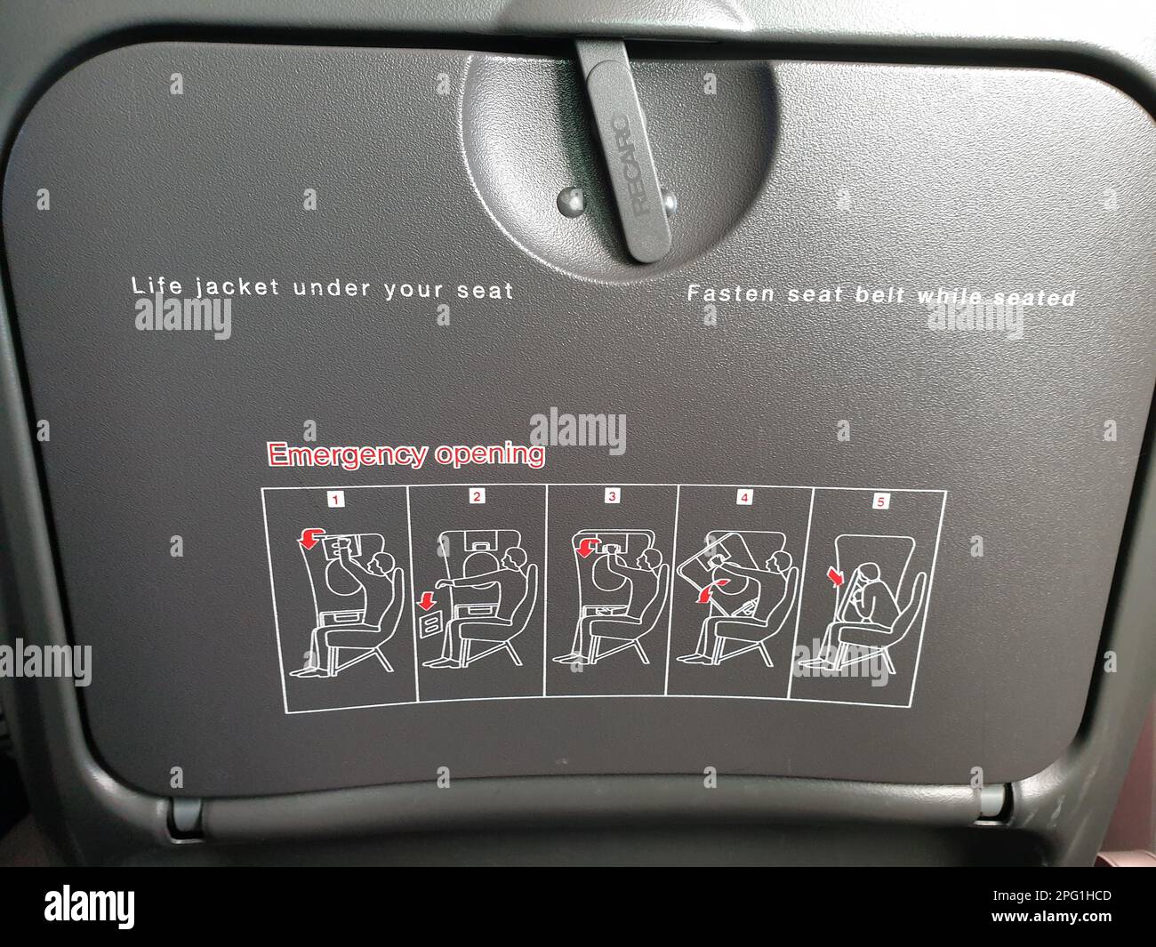 Anweisungen zum Öffnen von Nottüren auf dem Tablett-Tisch der Sitzplätze im Notausstiegsbereich an Bord eines airbus-Flugzeugs während des mittleren Fluges Stockfoto