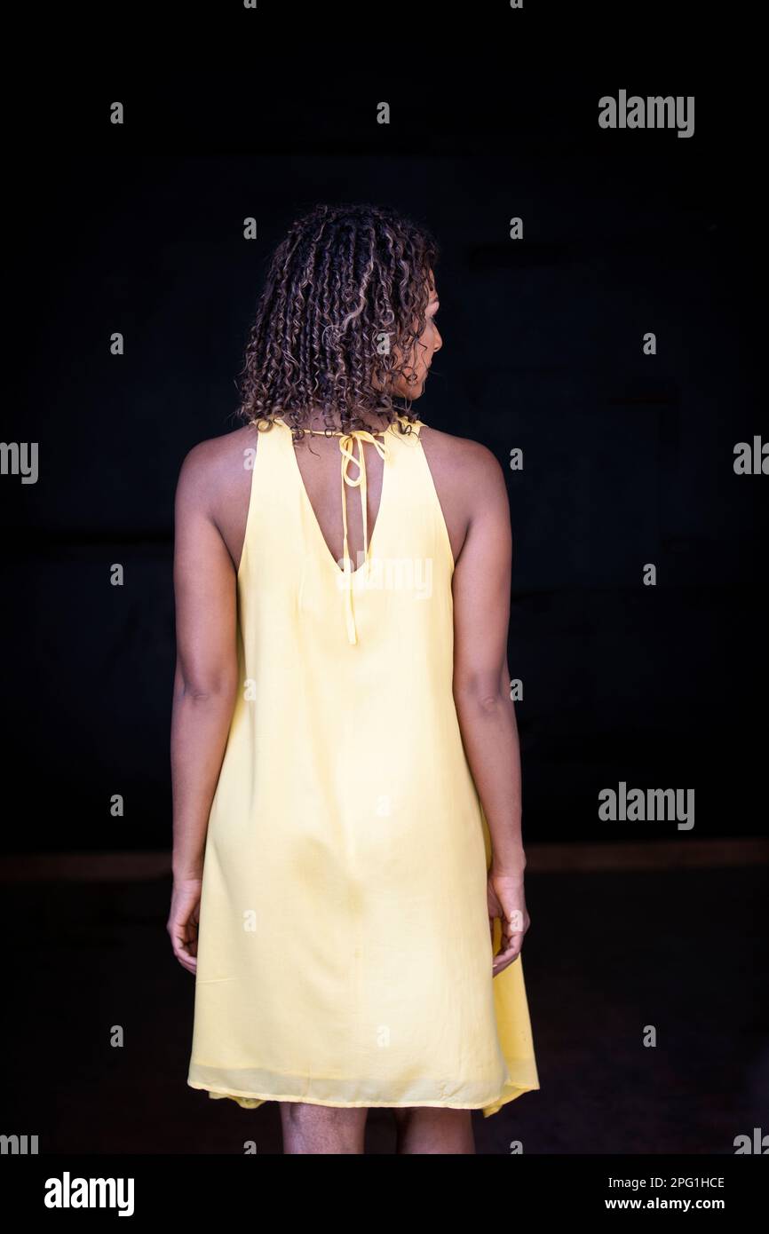 Rückansicht einer schwarzen Frau in gelbem Kleid Stockfoto