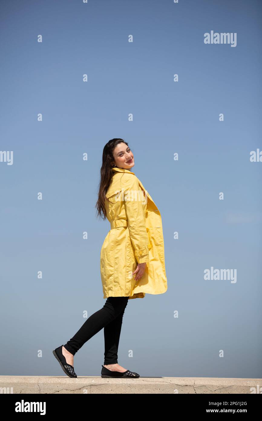 Schöne Frau im gelben Mantel, die draußen lächelt Stockfoto