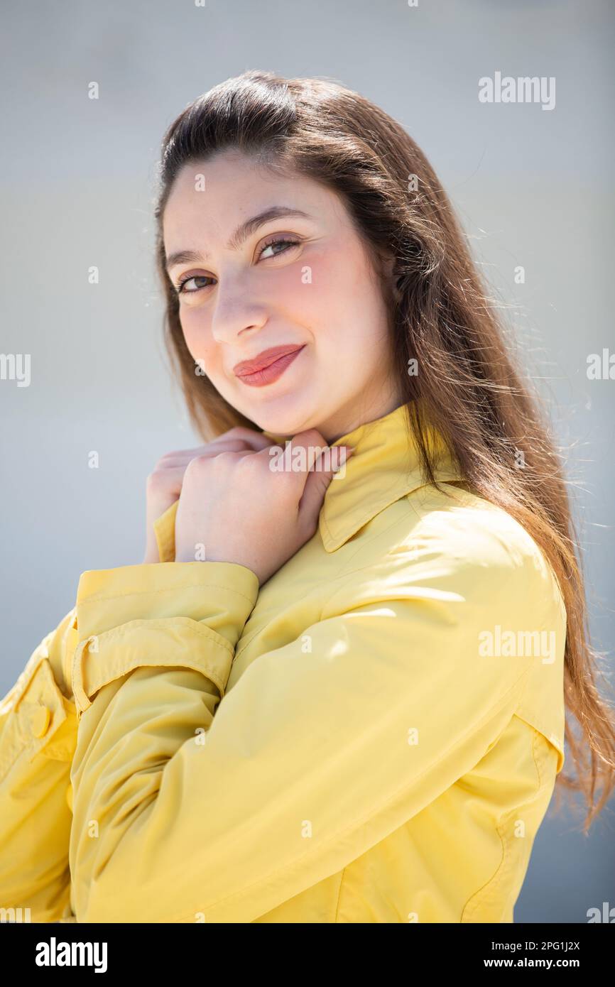 Schöne Frau im gelben Mantel, die draußen lächelt Stockfoto