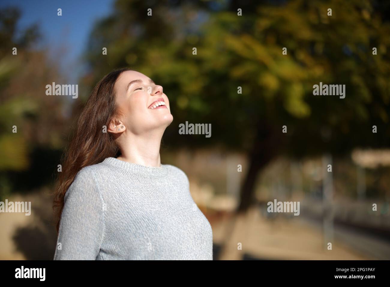 Glückliche alleinstehende Frau, die im Park frische Luft atmet Stockfoto