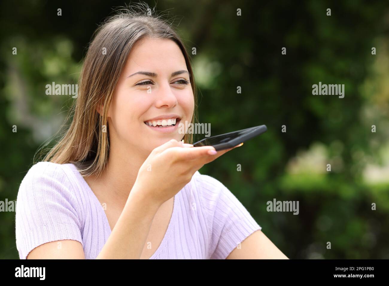 Teenager diktieren Nachrichten auf dem Handy draußen in einem Park Stockfoto