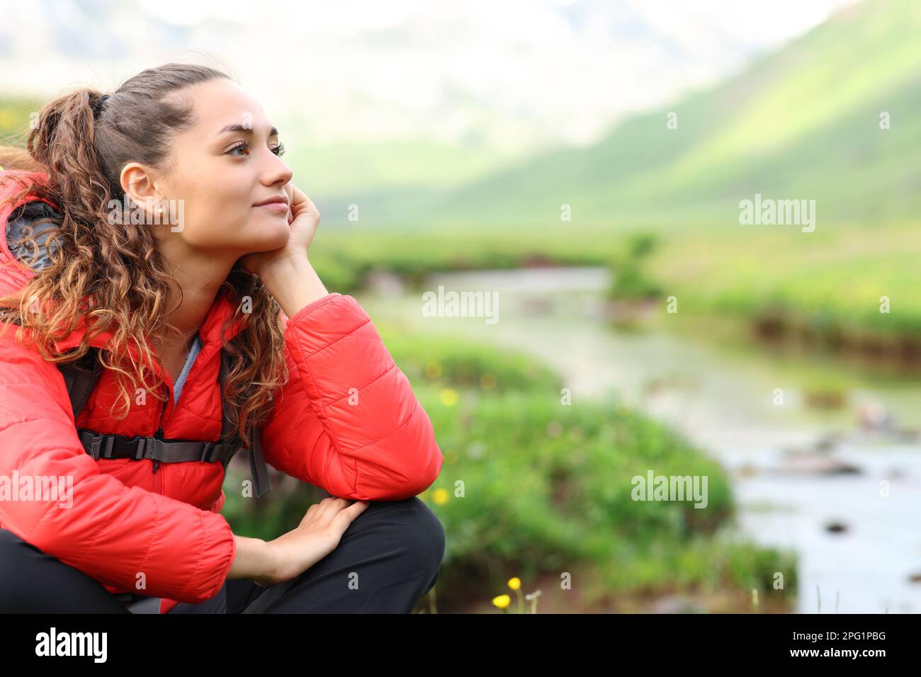 Entspannter Wanderer in Rot, der sich ausruht und die Aussicht auf die Natur betrachtet Stockfoto