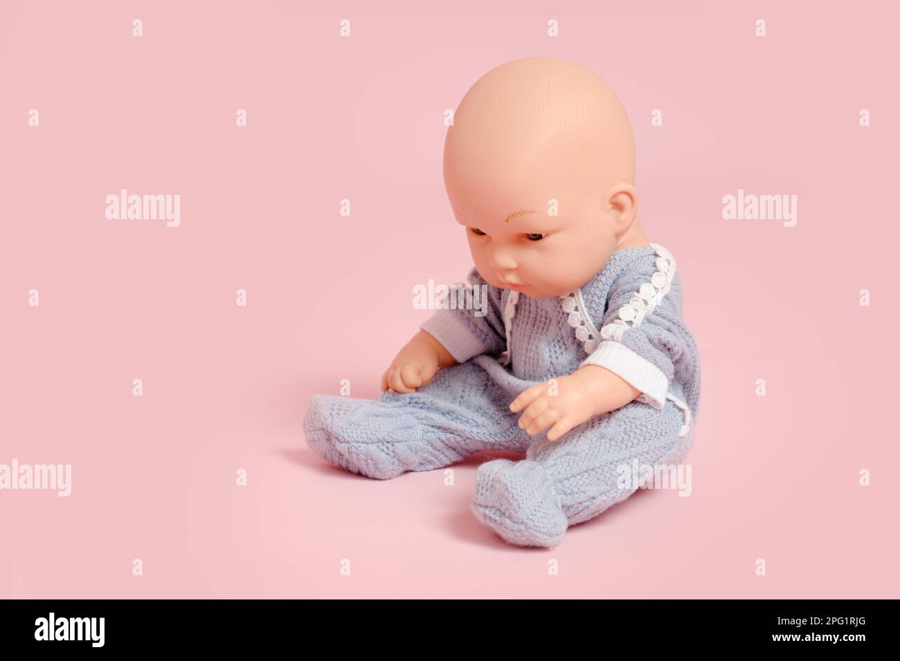 Baby-Puppe mit Glatze auf rosa Studiohintergrund. Kinderspielzeug ohne Haare, Kopierbereich Stockfoto