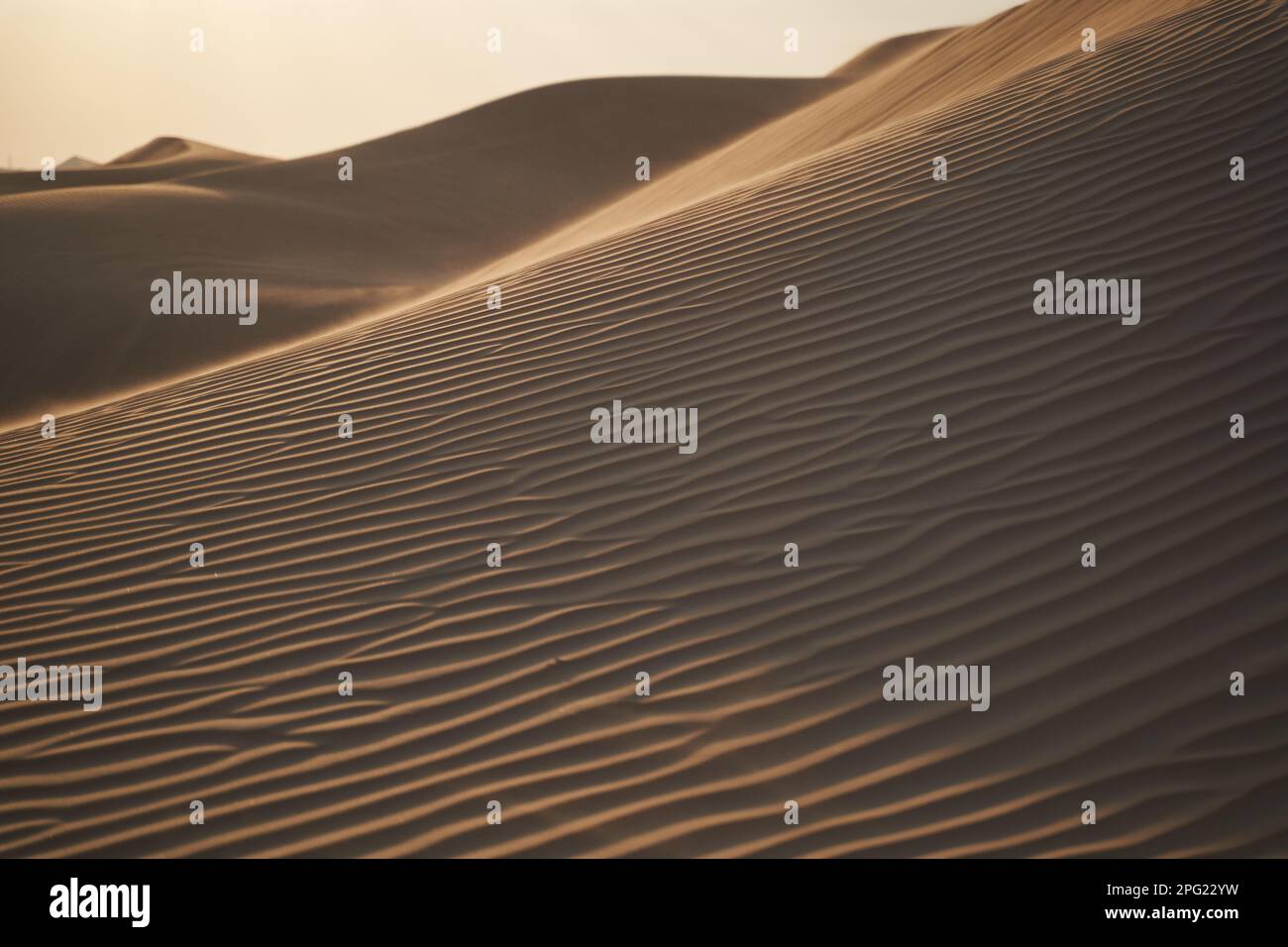 Minimalistische Landschaft mit Sandmustern, Dünen und der untergehenden Sonne. Stockfoto