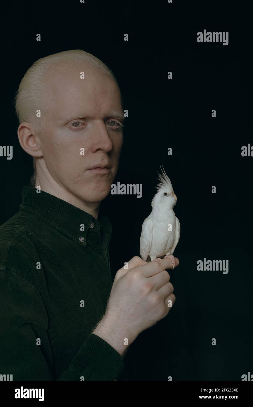 Ein Albino mit einem weißen Papagei auf dunklem Hintergrund Stockfoto