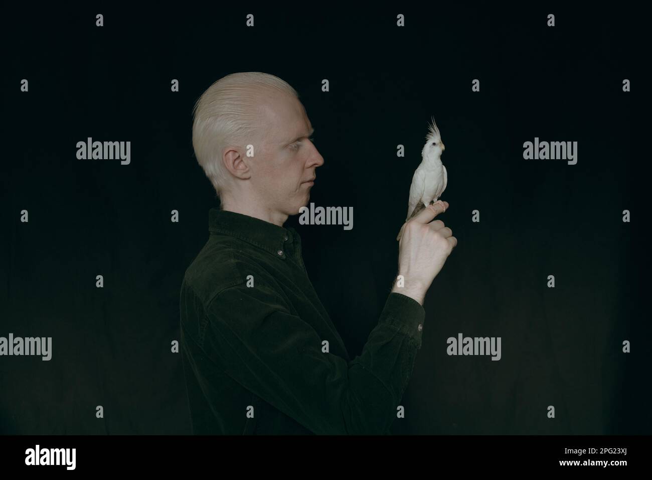 Ein Albino mit einem weißen Papagei auf dunklem Hintergrund Stockfoto