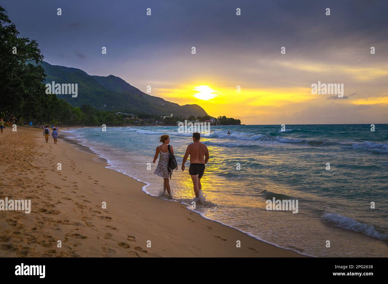Ein Paar, das am Beau Vallon Beach bei Sonnenuntergang spaziert, Insel Mahe, Seychellen Stockfoto
