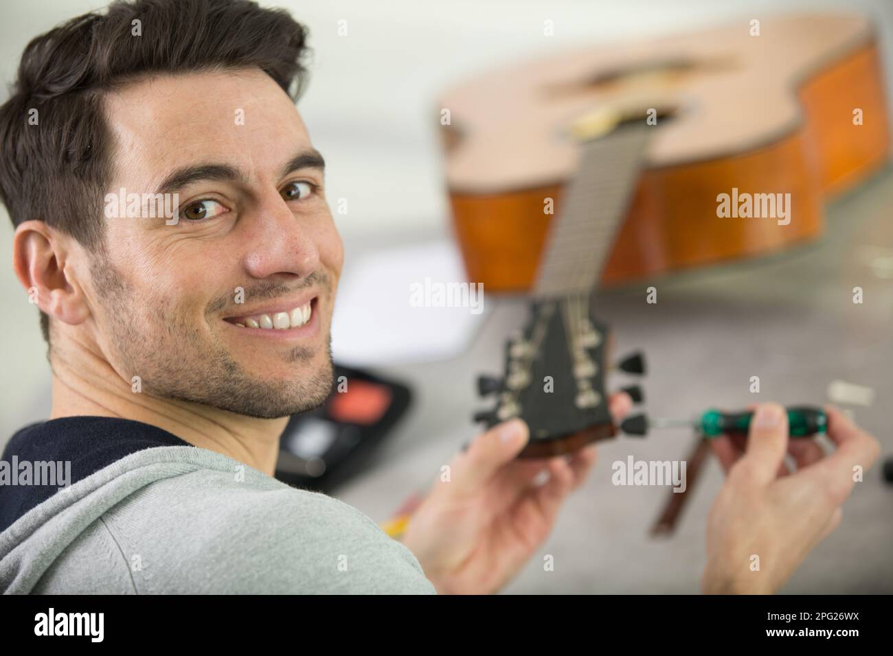 Junge gut aussehende Werkstatt Reparatur Gitarre Stockfoto