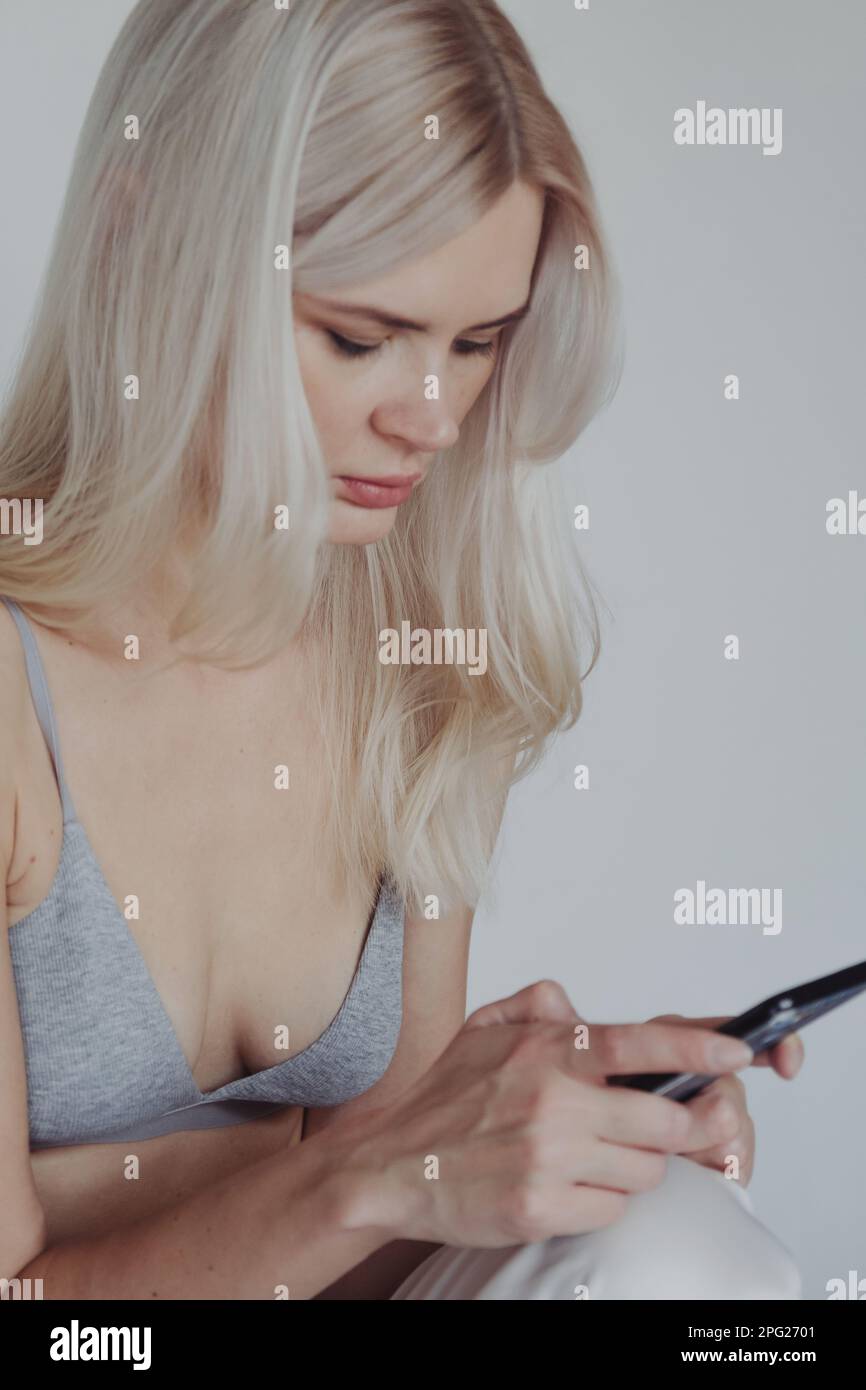Blonde Frau in einem BH mit Telefon Stockfoto