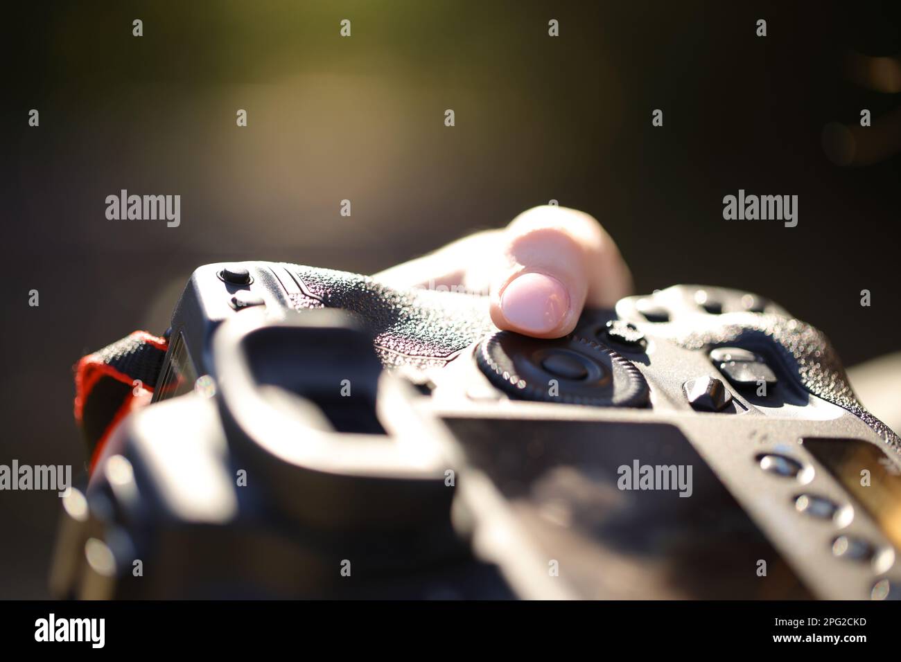 Fotograf, der die Blendenöffnung mit dem Finger der Kamera justiert Stockfoto