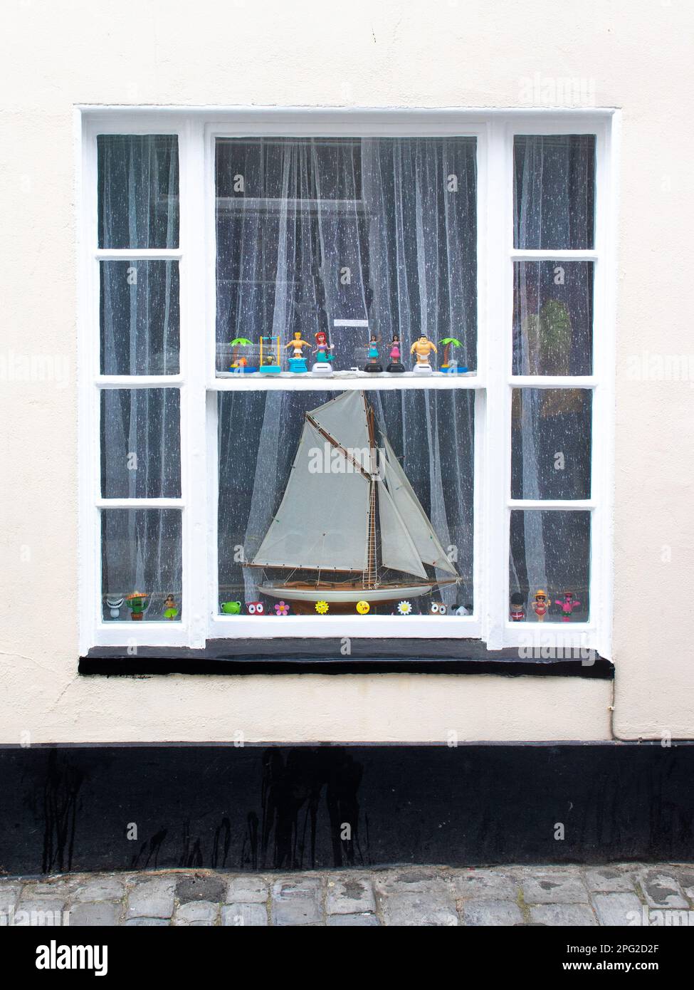 Ein Fenster am Meer mit Modellsegler in der Küstenstadt Lyme Regis in Dorset. Stockfoto