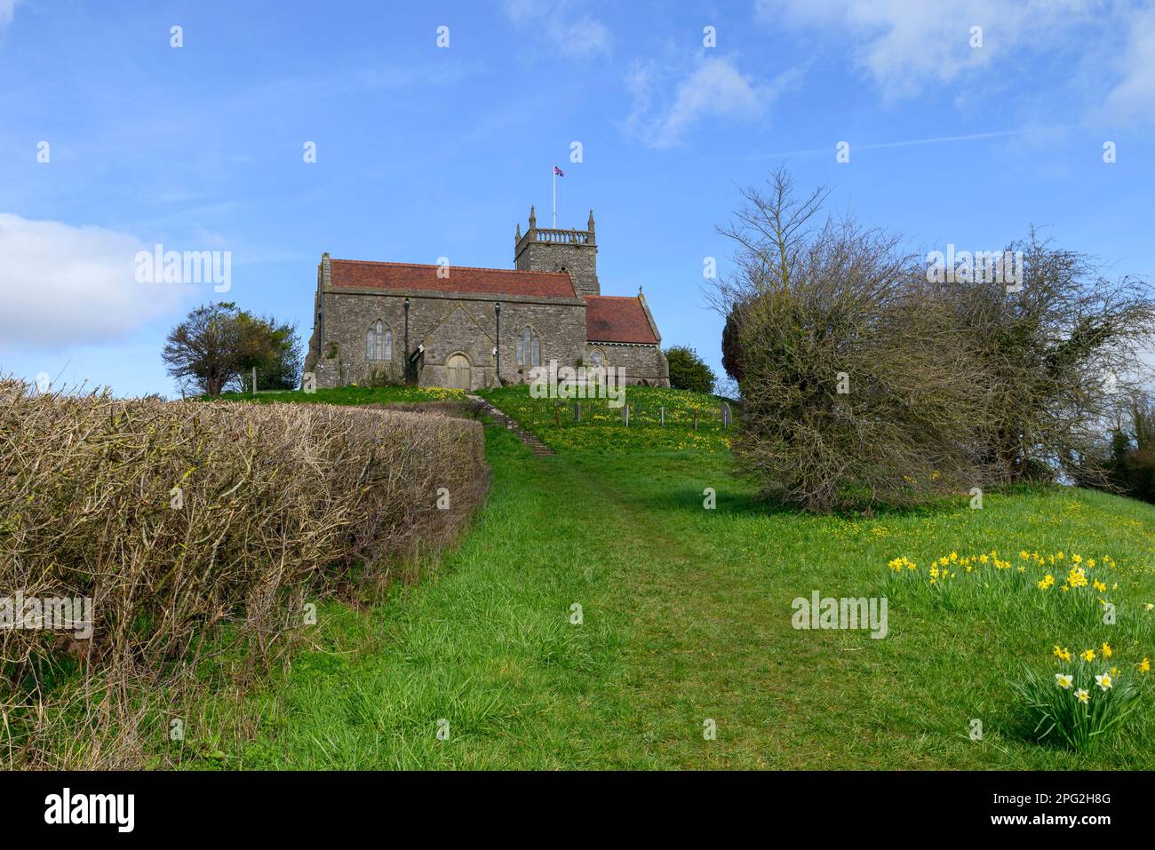 St. Arilda Kirche auf einem Hügel, Oldbury-on-Severn, South Gloucestershire, England, Großbritannien, mit Frühlingsnarzissen im März Stockfoto